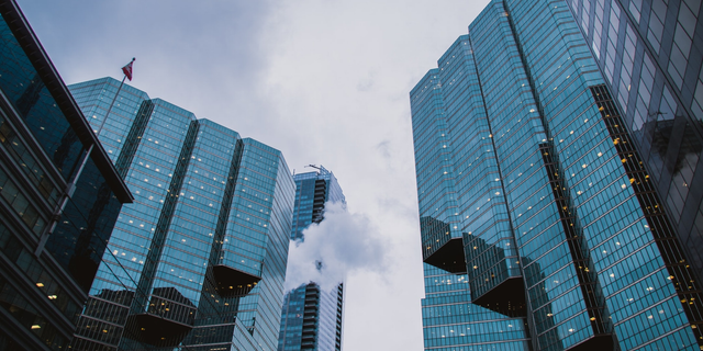 Um conjunto de arranha-céus com faixada de vidro em ângulo que nos leva a olhar para cima
